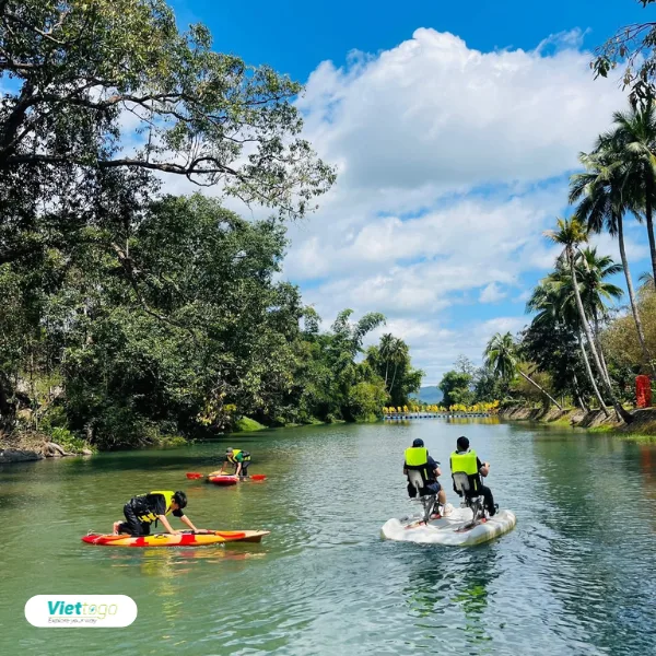 Hoạt động chèo kayak và đạp xe nước trên sông giữa rừng dừa xanh